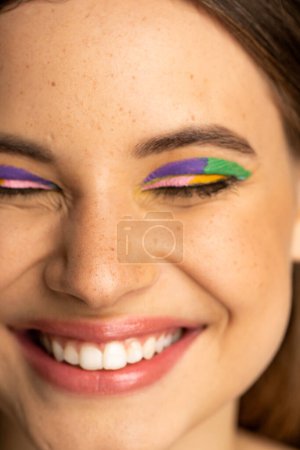 Close up view of cheerful teen girl with colorful visage closing eyes