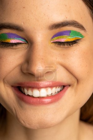 Close up view of cheerful teenager with bright makeup and closed eyes 