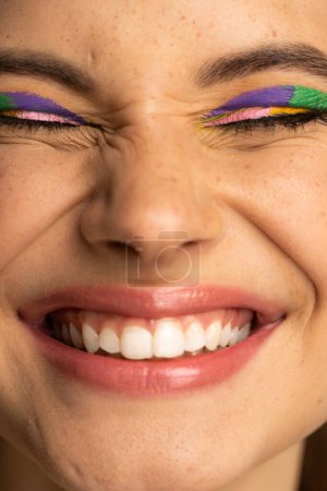 Cropped view of cheerful teen model with colorful makeup and freckles
