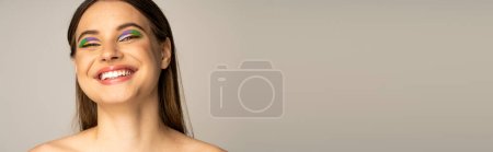 Photo for Teen model with colorful visage smiling at camera isolated on grey, banner - Royalty Free Image