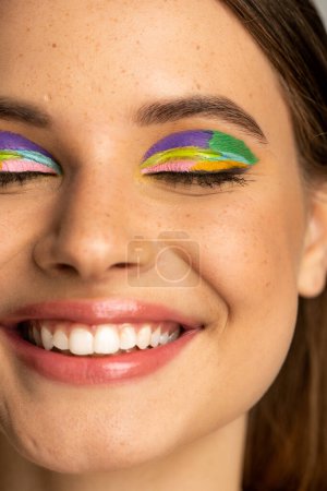 Cropped view of freckled teenage girl with colorful makeup 