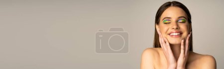 Photo for Teenage model with multicolored eyeshadows touching face isolated on grey, banner - Royalty Free Image