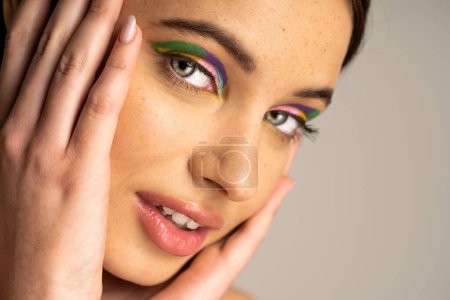 Téléchargez les photos : Portrait of freckled teen model with creative visage looking at camera isolated on grey - en image libre de droit