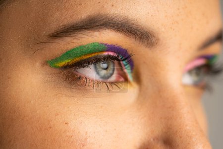 Cropped view of teen girl with freckles and colorful eyeshadows isolated on grey 