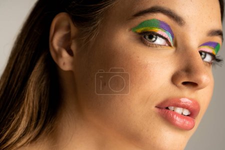 Portrait of teen model with colorful visage standing isolated on grey 