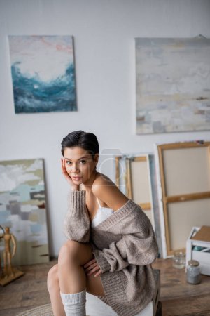 Short haired sexy artist looking at camera while sitting in workshop 
