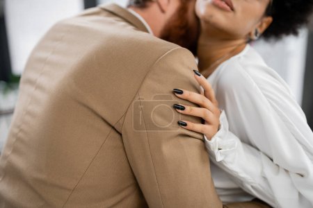 cropped view of bearded man kissing neck of african american woman in office 