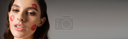 Photo for Portrait of young woman with makeup and red lipstick marks on face isolated on grey, banner - Royalty Free Image