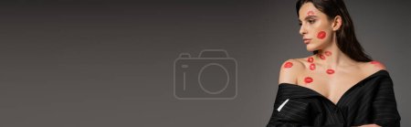 Photo for Pretty woman with red lipstick marks on naked shoulders posing in black oversize blazer isolated on grey, banner - Royalty Free Image