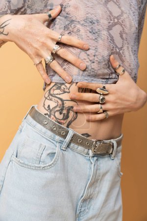 Cropped view of tattooed queer person posing isolated on yellow 