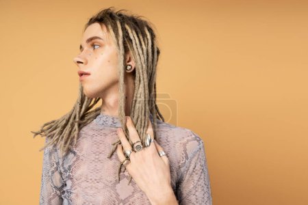Photo for Stylish queer person touching dreadlocks isolated on yellow - Royalty Free Image