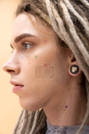 Photo for Portrait of young queer person with tattoo on face looking away isolated on yellow - Royalty Free Image