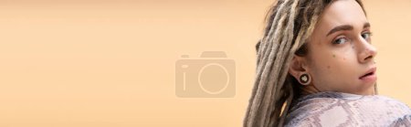 Young nonbinary person with dreadlocks looking at camera isolated on yellow, banner 