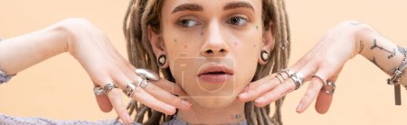 Nonbinary person with dreadlocks and rings on fingers isolated on yellow, banner 