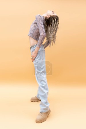 Photo for Side view of stylish queer person with dreadlocks posing on yellow background - Royalty Free Image