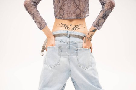 Photo for Cropped view of tattooed queer person holding hands in pockets of jeans isolated on white - Royalty Free Image