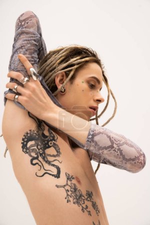 Téléchargez les photos : Tattooed queer person in crop top with animal print touching arm isolated on white - en image libre de droit