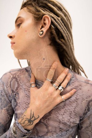 Téléchargez les photos : Side view of young tattooed queer person touching neck isolated on white - en image libre de droit