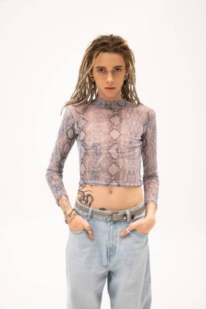 Téléchargez les photos : Tattooed queer person in crop top and jeans looking at camera isolated on white - en image libre de droit
