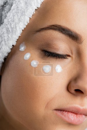 Foto de Close up view of woman with towel on head and face cream - Imagen libre de derechos