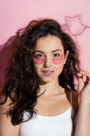 Photo for Curly young woman with hydrogel eye patches on pink background - Royalty Free Image