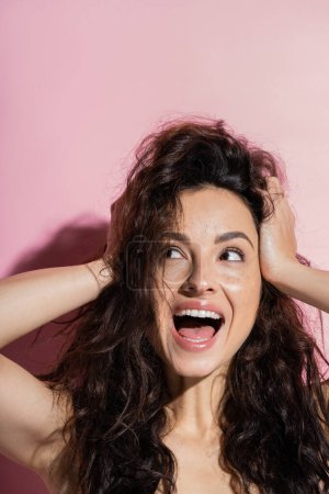 Foto de Excited brunette woman with freckled looking away on pink background - Imagen libre de derechos