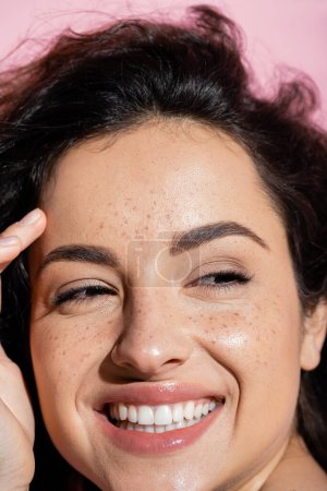 Photo for Close up view of positive woman with freckles touching skin isolated on pink - Royalty Free Image