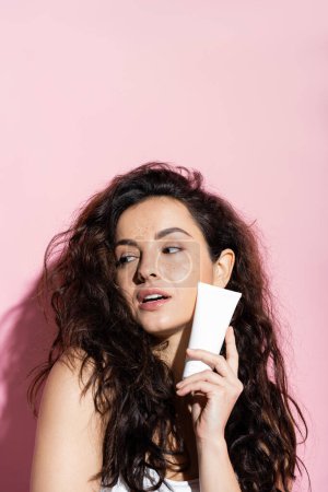 Photo for Pretty woman with freckled skin holding cosmetic cream on pink background - Royalty Free Image