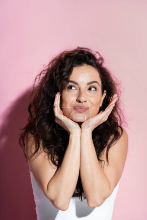 Photo for Joyful curly woman looking away on pink background - Royalty Free Image