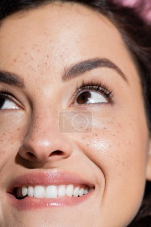 Cropped view of dreamy and freckled woman looking up 