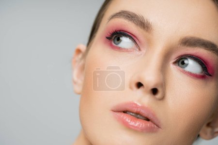 close up portrait of pretty woman with perfect skin and makeup looking away isolated on grey