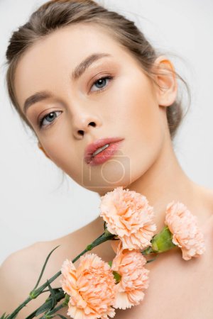 Photo for Portrait of young and charming woman with perfect face looking at camera near fresh flowers isolated on grey - Royalty Free Image