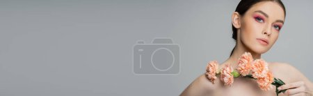 Photo for Young woman with naked shoulders and makeup holding fresh carnations isolated on grey, banner - Royalty Free Image