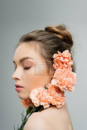 Photo for Young woman with closed eyes and natural makeup near fresh carnations isolated on grey - Royalty Free Image