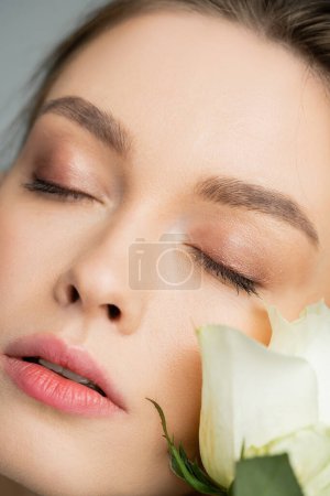 Téléchargez les photos : Close up portrait of young woman with closed eyes near fresh rose - en image libre de droit