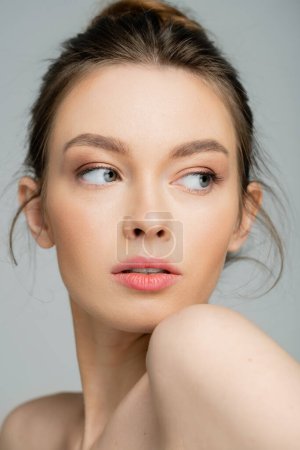 Portrait of pretty woman with natural makeup looking away isolated on grey 