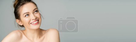 Pretty fair haired woman with naked shoulders looking up isolated on grey, banner 