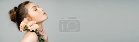 Photo for Young woman with perfect skin posing near carnations isolated on grey, banner - Royalty Free Image