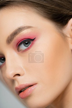 Téléchargez les photos : Cropped view of woman with pink eye shadow and eye liner looking at camera isolated on grey - en image libre de droit