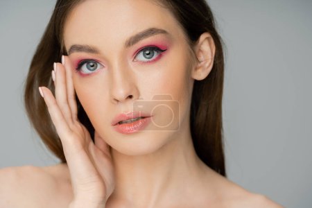 Téléchargez les photos : Portrait of young woman with pink makeup touching face isolated on grey - en image libre de droit