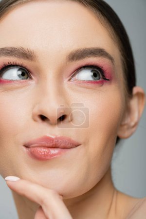 Close up view of dreamy young woman with pink visage isolated on grey 