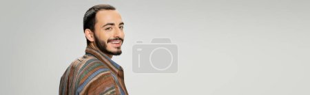 portrait of happy bearded man in colorful shirt smiling at camera isolated on grey, banner