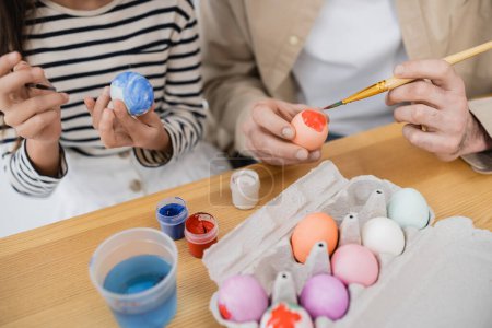 Vista recortada de niña y papá para colorear huevos de Pascua en casa 