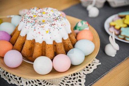 Easter cake and colorful painted eggs on plate at home 