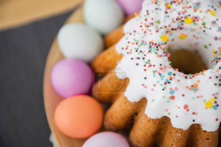 Top view of sweet Easter cake and colorful eggs on table 