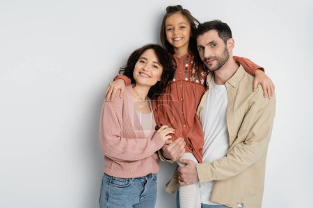 Smiling preteen girl hugging parents on white background 