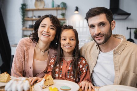Positive family looking at camera during Easter dinner at home 