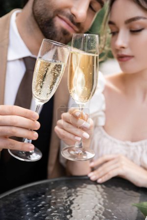 Photo for Young newlyweds clinking glasses of champagne during wedding celebration - Royalty Free Image