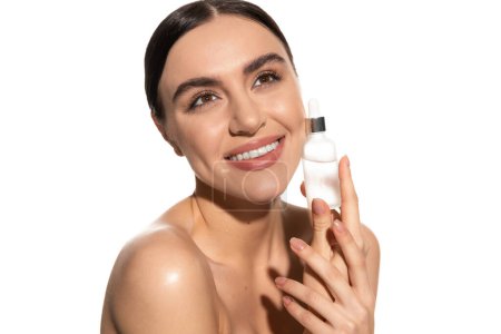 positive junge Frau mit natürlichem Make-up hält Flasche mit Serum isoliert auf weiß 