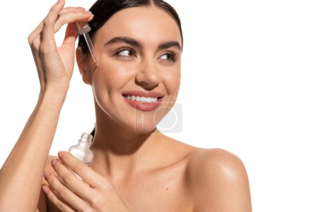 positive and brunette woman holding pipette with serum isolated on white  Poster 642937488